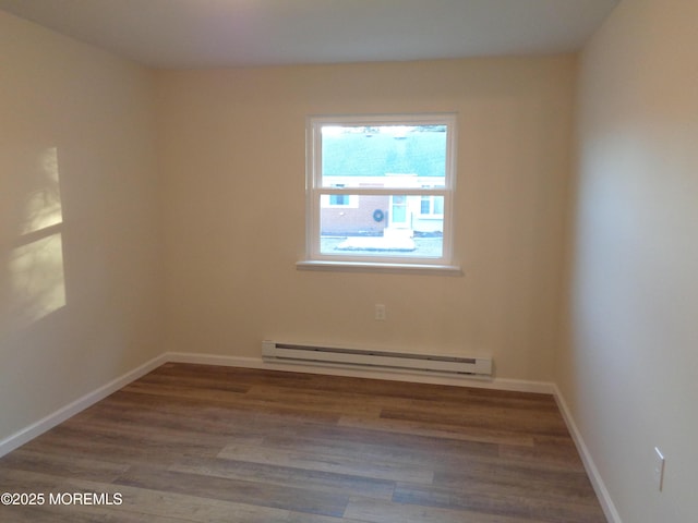 unfurnished room with a baseboard heating unit, baseboards, and wood finished floors