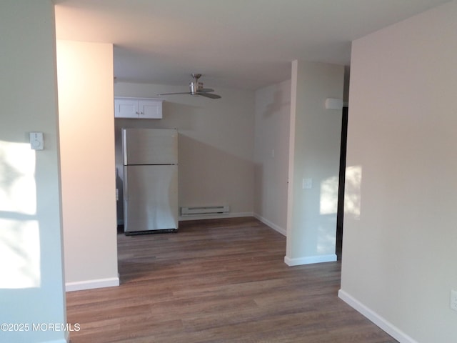 empty room with baseboards, a ceiling fan, baseboard heating, and wood finished floors