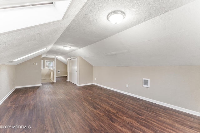 bonus room featuring lofted ceiling, dark wood finished floors, visible vents, and baseboards