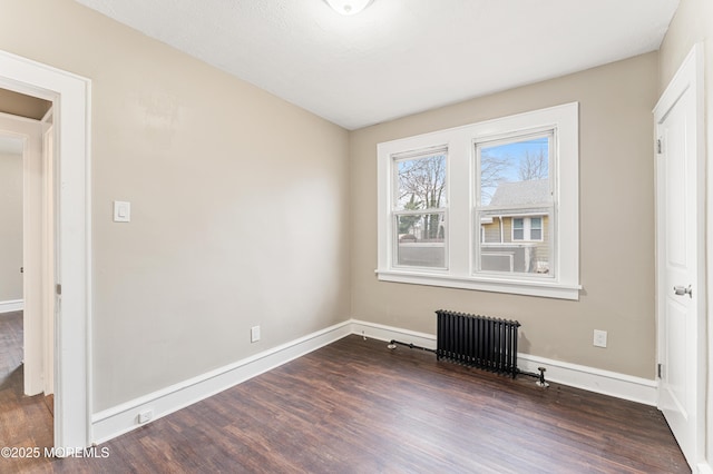 interior space featuring radiator, dark wood finished floors, and baseboards