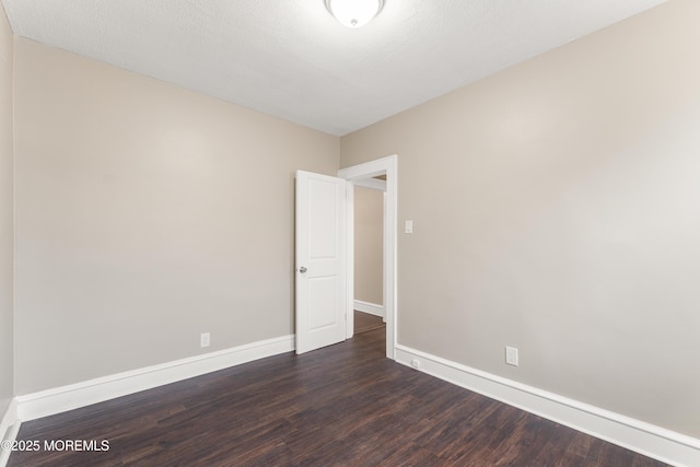 empty room featuring dark wood-style floors, baseboards, and a textured ceiling