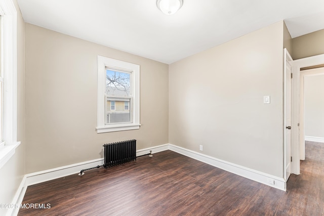 unfurnished room with baseboards, wood finished floors, and radiator