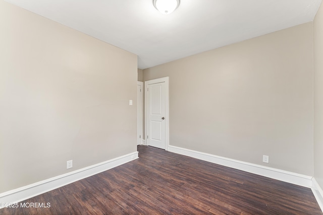 spare room featuring baseboards and dark wood-style flooring