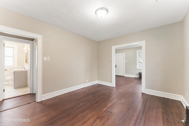 unfurnished room with dark wood-style flooring and baseboards