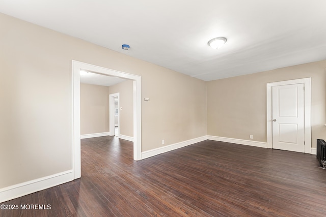 empty room with dark wood finished floors and baseboards