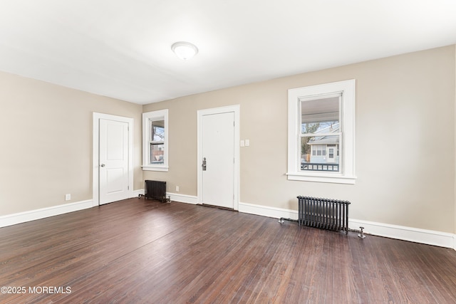 unfurnished room with baseboards, radiator heating unit, and wood finished floors