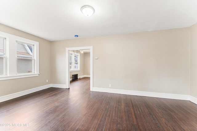 unfurnished room featuring dark wood-style floors, plenty of natural light, and baseboards