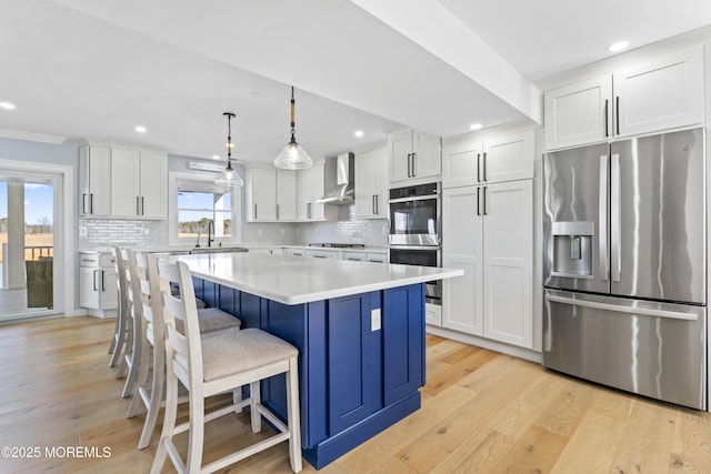 45 Royal Dr, Brick, NJ 08723 - kitchen with stainless steel appliances, wall chimney range hood, light wood finished floors, white cabinets, and backsplash