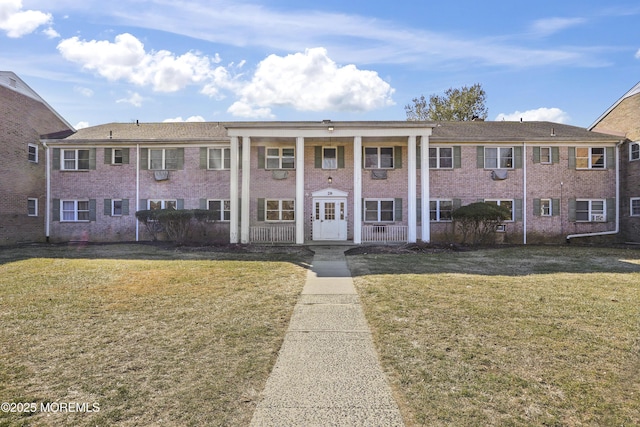 view of front of home with covered porch, brick siding, and a front yard