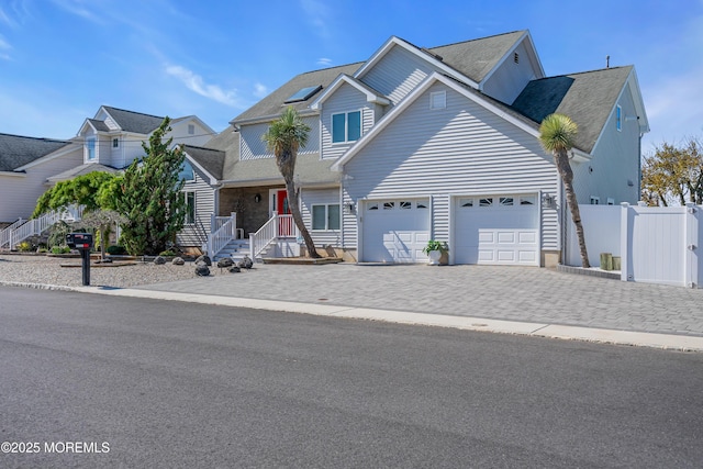 view of front facade with a garage, decorative driveway, and fence