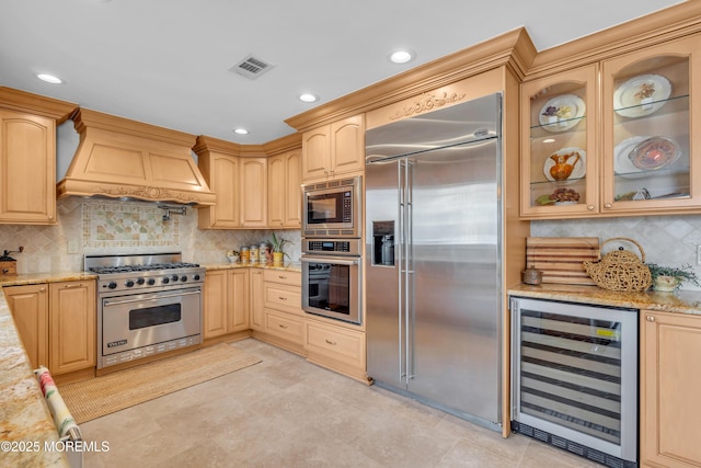 kitchen with light stone counters, wine cooler, custom exhaust hood, visible vents, and built in appliances