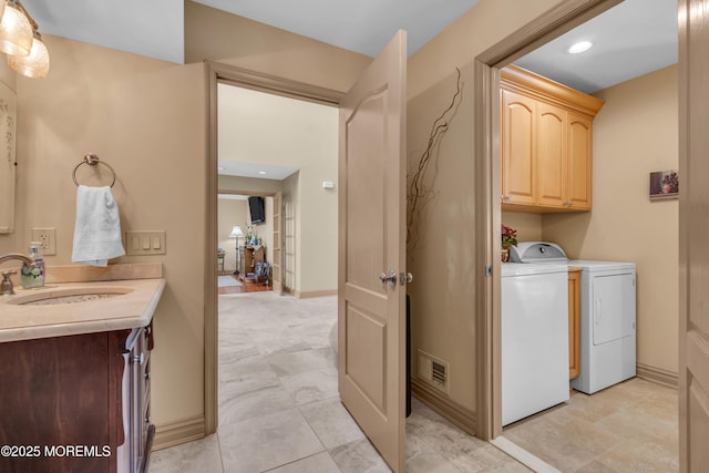 washroom with baseboards, visible vents, a sink, and washing machine and clothes dryer