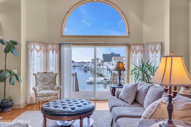 living room featuring a water view, a high ceiling, and wood finished floors