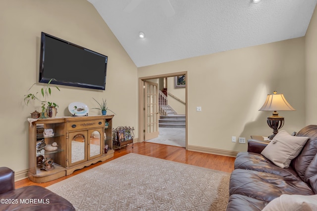 living area featuring stairs, wood finished floors, lofted ceiling, and baseboards