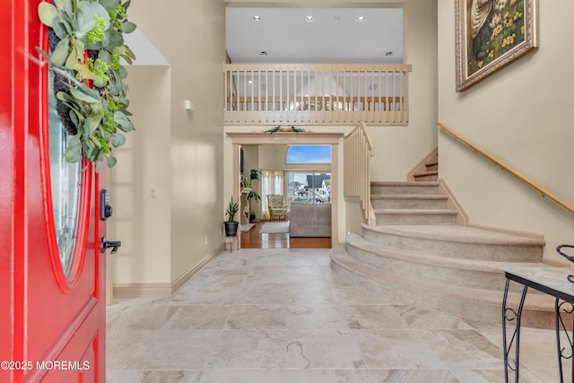 entryway with baseboards, a high ceiling, and stairway