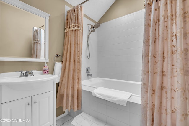 bathroom with vaulted ceiling, a textured ceiling, tiled shower / bath combo, vanity, and tile patterned floors