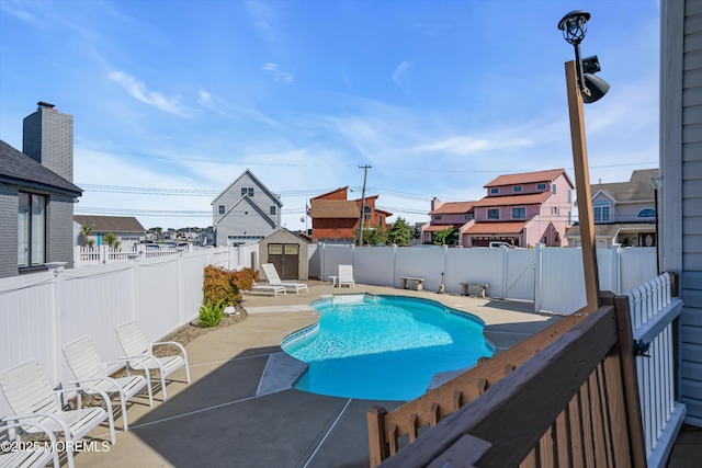 view of swimming pool with a shed, a patio area, a fenced backyard, and an outdoor structure