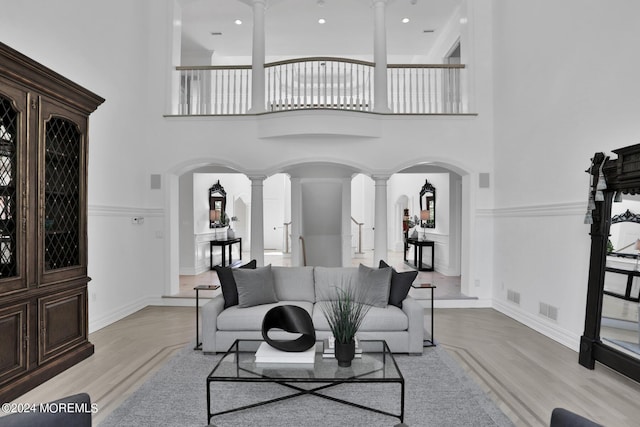 living area with arched walkways, a high ceiling, visible vents, and decorative columns