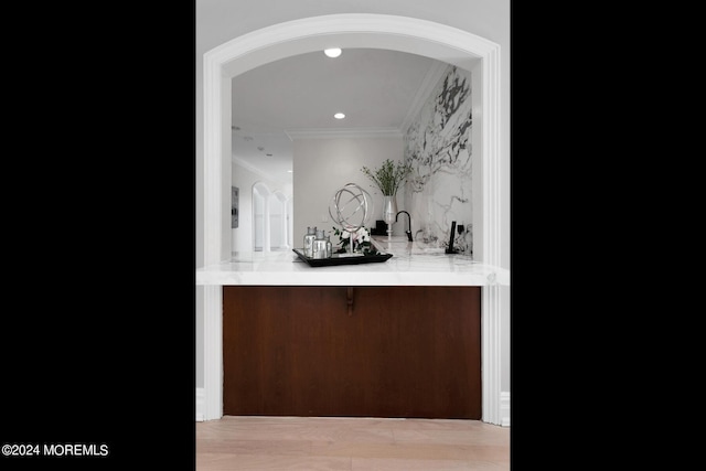 bar with arched walkways, crown molding, wet bar, and recessed lighting