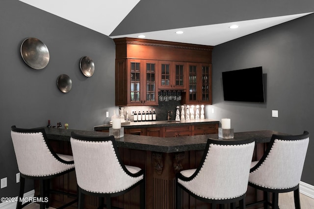 bar with recessed lighting, baseboards, vaulted ceiling, wet bar, and tasteful backsplash