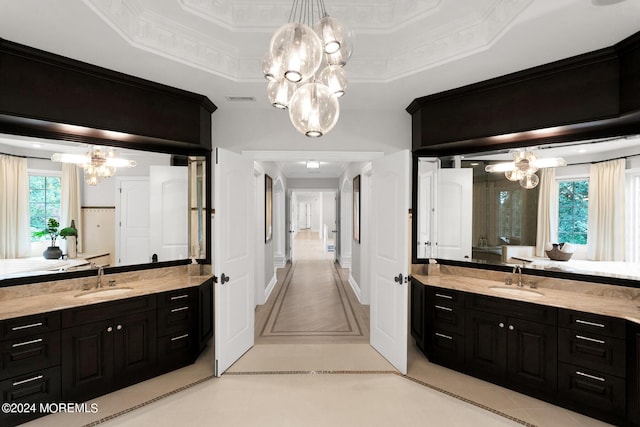 full bath with crown molding, a raised ceiling, a notable chandelier, and a sink