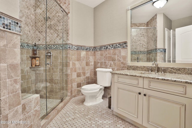 full bath with tile patterned flooring, toilet, vanity, tile walls, and a shower stall