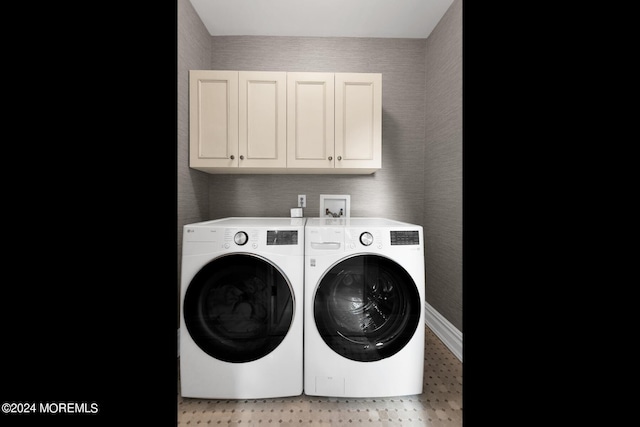 clothes washing area featuring baseboards, wallpapered walls, cabinet space, and washer and dryer