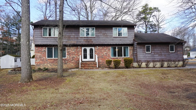 rear view of house featuring a chimney, a lawn, french doors, and brick siding