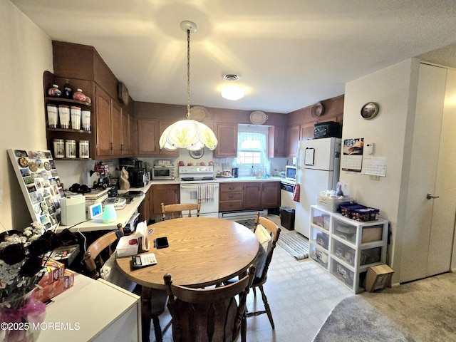 kitchen with white appliances, visible vents, hanging light fixtures, light countertops, and light floors