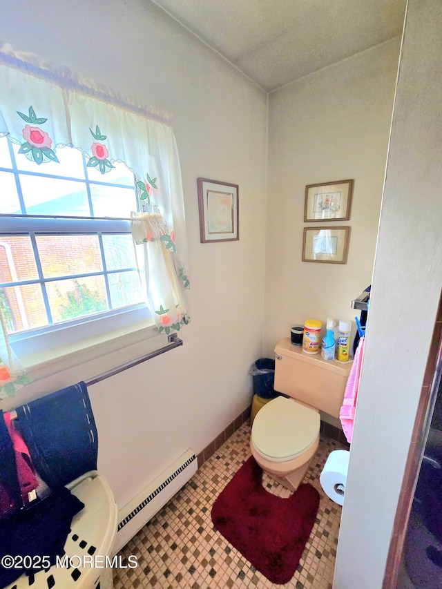 bathroom with toilet, baseboards, a baseboard heating unit, and tile patterned floors