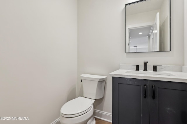 bathroom featuring toilet, vanity, and baseboards