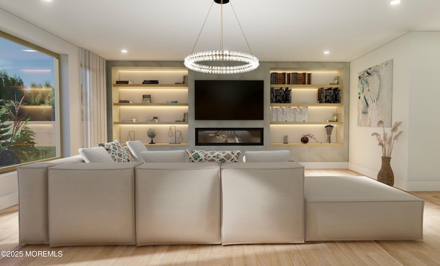 living area with built in features, recessed lighting, a glass covered fireplace, wood finished floors, and baseboards