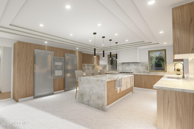 kitchen featuring a large island, a raised ceiling, appliances with stainless steel finishes, a sink, and modern cabinets