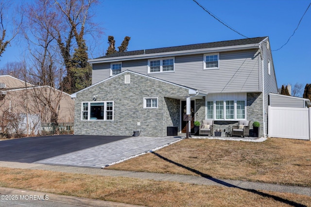 view of front of property featuring stone siding, fence, outdoor lounge area, and a patio