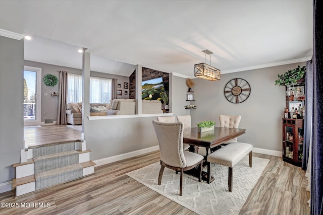 dining room featuring light wood-type flooring, baseboards, and crown molding