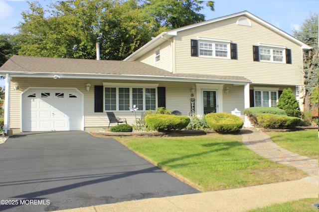 view of front of property with an attached garage, driveway, and a front lawn