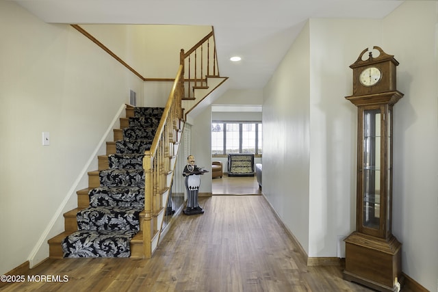 staircase with visible vents, baseboards, wood finished floors, and recessed lighting