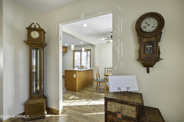 corridor with light wood-style floors, recessed lighting, and baseboards