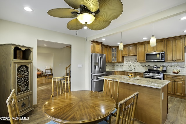 kitchen featuring a sink, stainless steel appliances, brown cabinetry, and wood finished floors