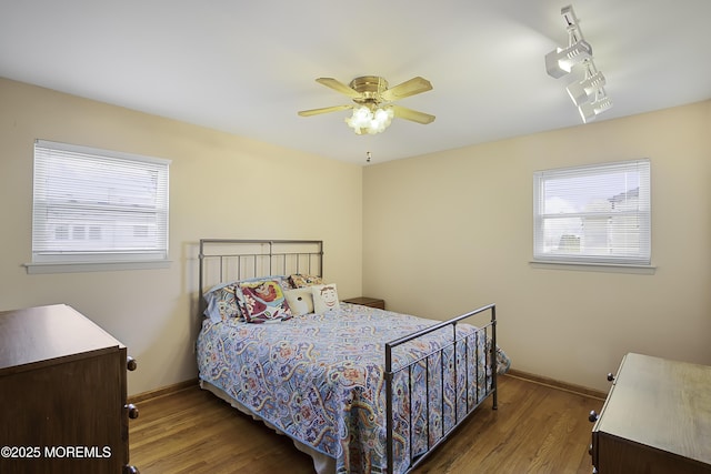 bedroom featuring multiple windows, baseboards, and wood finished floors