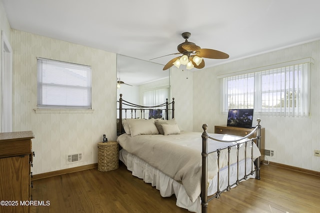 bedroom with wood finished floors, visible vents, and wallpapered walls