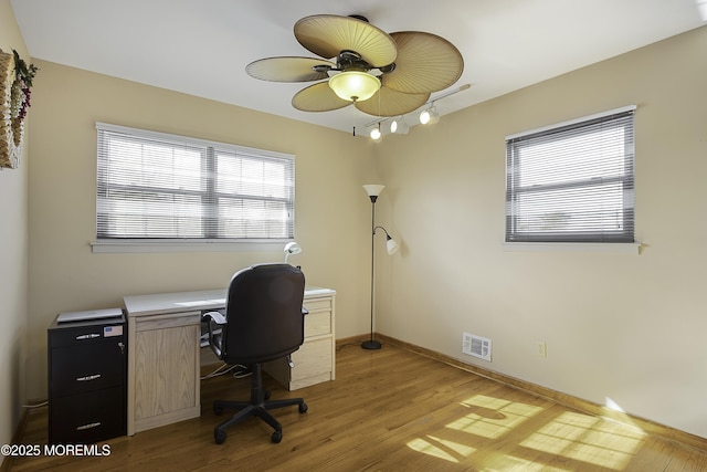 office featuring light wood finished floors, a ceiling fan, visible vents, and baseboards