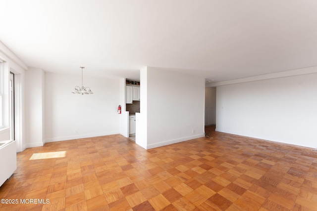 unfurnished room featuring baseboards and a chandelier