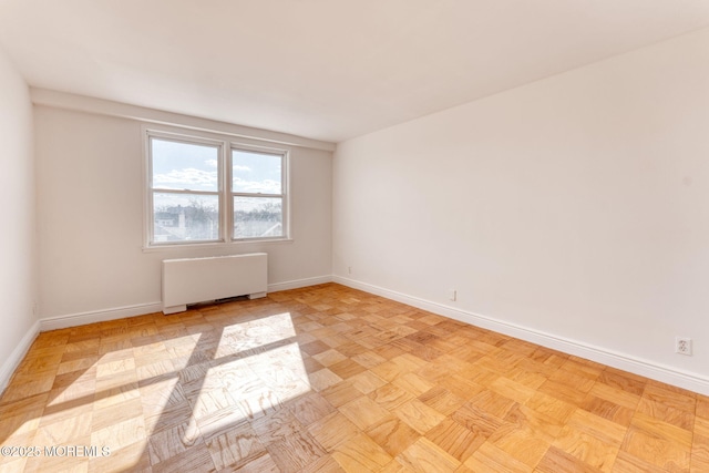 spare room featuring radiator and baseboards