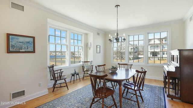 dining space with visible vents, crown molding, baseboards, and wood finished floors