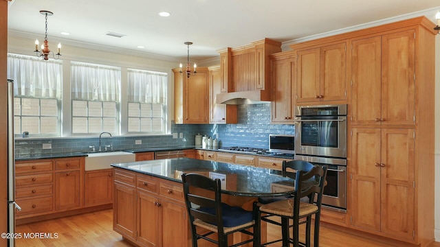 kitchen with appliances with stainless steel finishes, light wood-style floors, a notable chandelier, and a sink