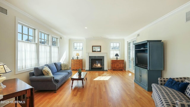 living room with light wood-style floors, visible vents, a fireplace, and ornamental molding