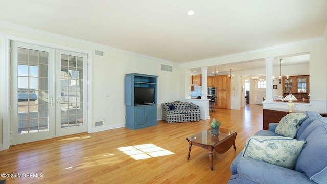 living room featuring light wood-style floors, visible vents, and an inviting chandelier