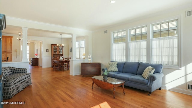 living area with a chandelier, light wood-style flooring, visible vents, baseboards, and crown molding