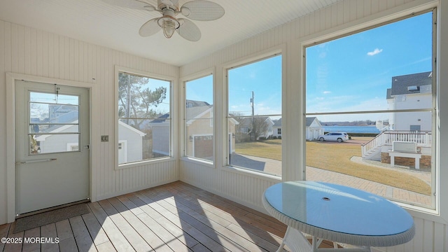 sunroom with a residential view and a ceiling fan